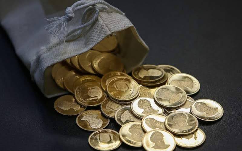 کیسه‌ نیمه‌باز بندی شکل و طوسی‌رنگ حاوی سکه‌های پارسیان و سکه‌های بانکی که روی پس‌زمینه‌ای مشکی ریخته شده است.