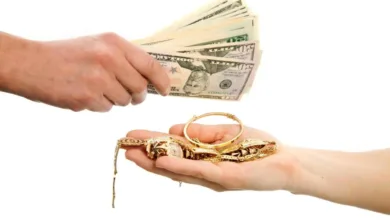 تصویر روبه‌رو از دست زنی که طلاهایش را به ازای دریافت چند اسکناس دلار از دست یک مرد طلافروش تحویل می‌دهد.