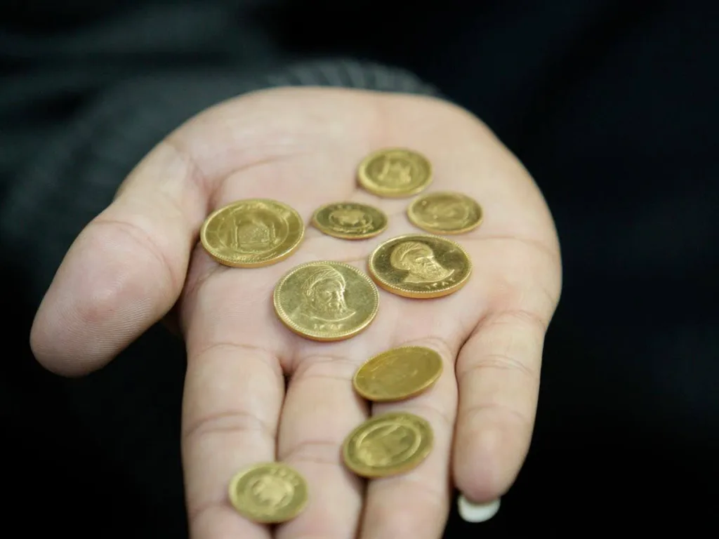 نمای از بالای ۹ سکه بانکی و غیر بانکی در کف دست یک خانم سکه فروش