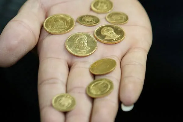 تعدادی سکه امامی به‌طور پراکنده کف دست یک سرمایه‌گذار بازاری
