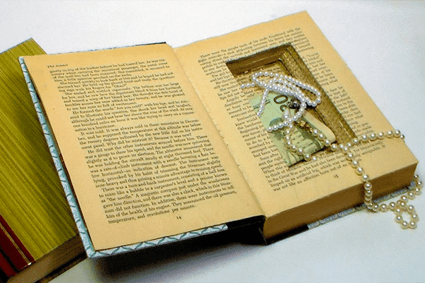 یک کتاب قطور انگلیسی با قالب صفحه‌ای بریده شده که برای نگهداری طلا و دلار مورد استفاده قرار گرفته است.