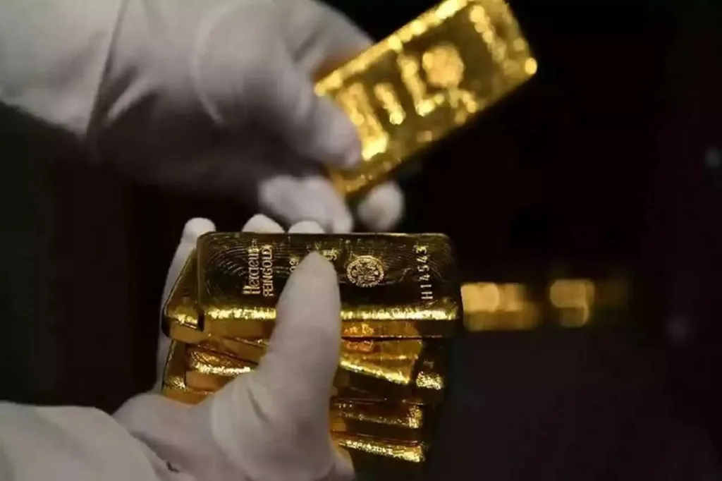 نمای کناری از دستان طلافروشی در حال شمردن چند شمش از انواع مصنوعات طلا