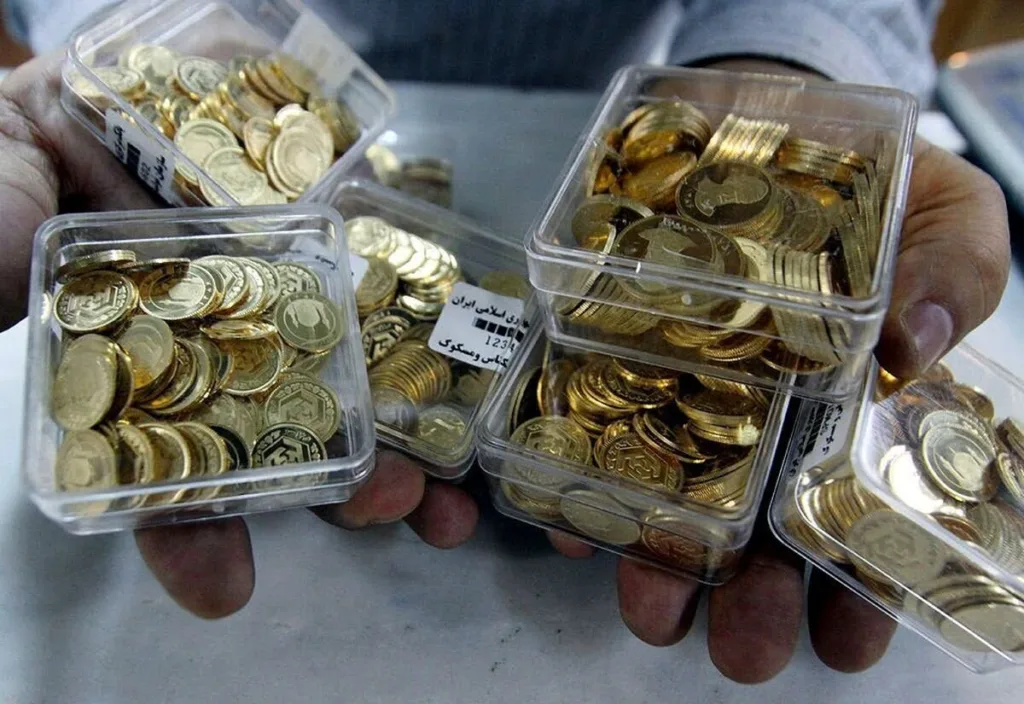نمای از بالای دستان فروشنده‌ در حال فروش چند جعبه پر از سکه بهار آزادی به متقاضیان سکه