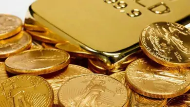 نمای روبه‌رو از تعدادی سکه ریخته شده کنار طلای آب شده ۱۹ عیار که به‌صورت شمش است.