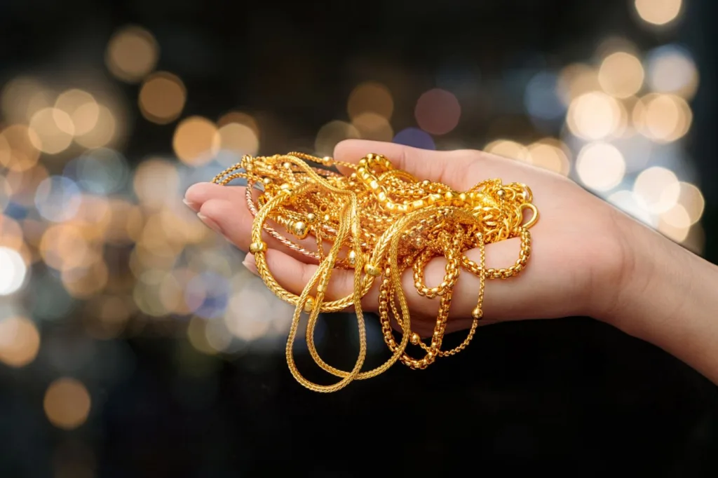 تصویر دست یک خانم از مچ و کف دست که روی کف دست او انواع زنجیر طلا به رنگ زرد قرار دارد.
