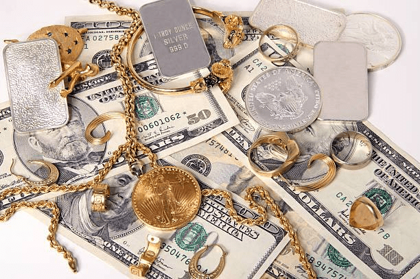 تعداد انگشتر و زنجیر و سکه و شمش طلا بر روی تعدادی اسکناس دلاری