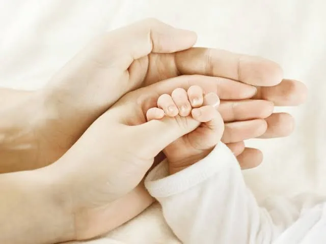 نمای روبه‌رو از دست چپ پدر پشت دست چپ مادر و دست نوزاد انگشت شست دست مادر را گرفته است. 
