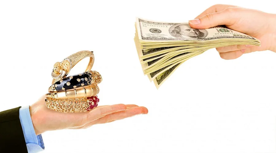 نمای نیم‌رخ از تحویل طلا شامل النگو و دستبند توسط کارمند بانک به مشتری در ازای بازپرداخت دلاری وام طلا
